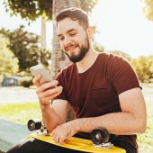 Young skater man using smartphone in the park