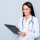 Young medical doctor writing diagnosis in her folder