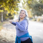 A senior Mexican woman stretching her legs